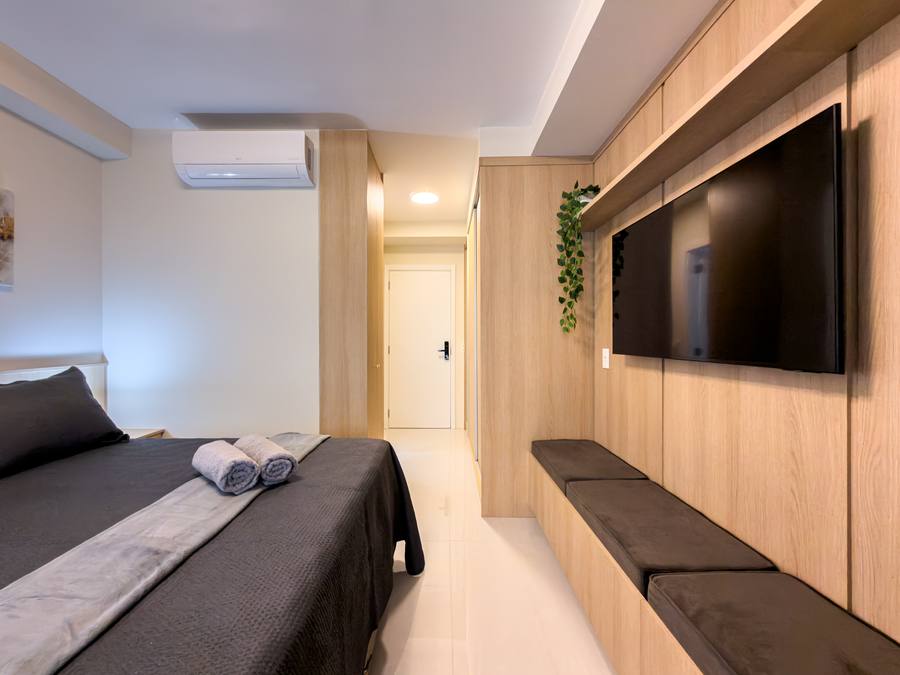 Quarto com TV no painel de madeira